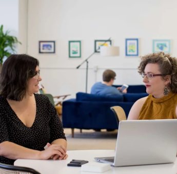 Two people talking in front of a laptop