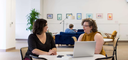 Two people talking in front of a laptop